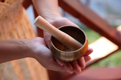Photo of Woman with singing bowl outdoors, closeup view