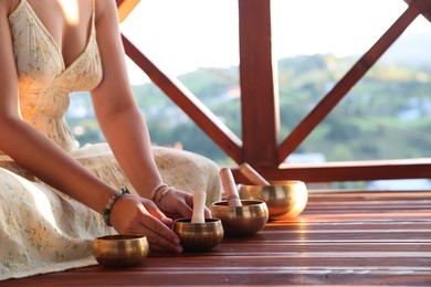 Photo of Woman with singing bowls on floor outdoors, closeup