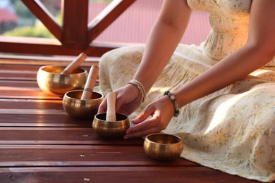 Photo of Woman with singing bowls on floor outdoors, closeup