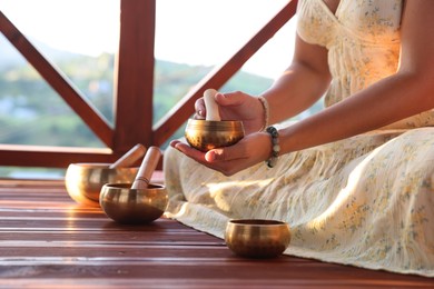 Photo of Woman with singing bowls on floor outdoors, closeup