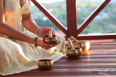 Photo of Woman with singing bowls on floor outdoors, closeup