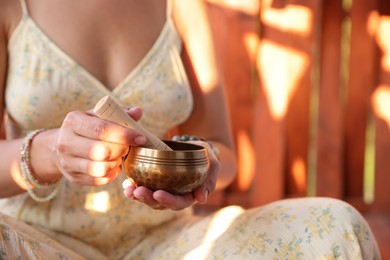 Photo of Woman with singing bowl outdoors on sunny day, closeup