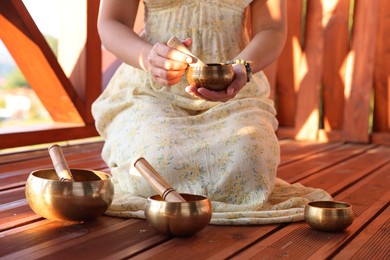 Photo of Woman with singing bowls on floor outdoors, closeup