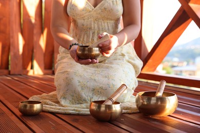Photo of Woman with singing bowls on floor outdoors, closeup
