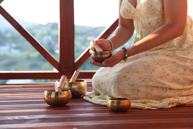 Photo of Woman with singing bowls on floor outdoors, closeup