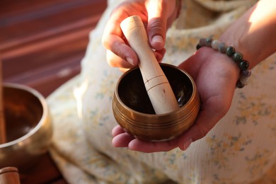 Photo of Woman with singing bowl outdoors, closeup view