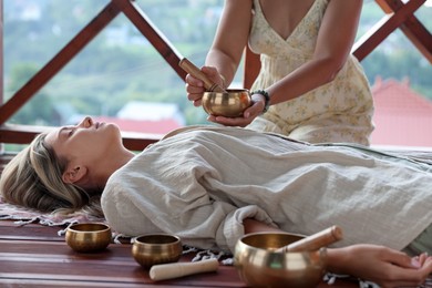 Photo of Woman undergoing singing bowl therapy lying on floor indoors