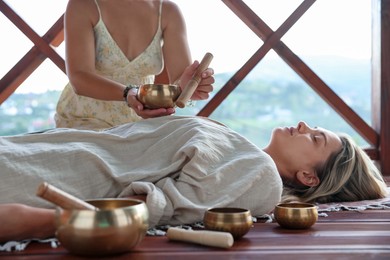 Photo of Woman undergoing singing bowl therapy lying on floor indoors