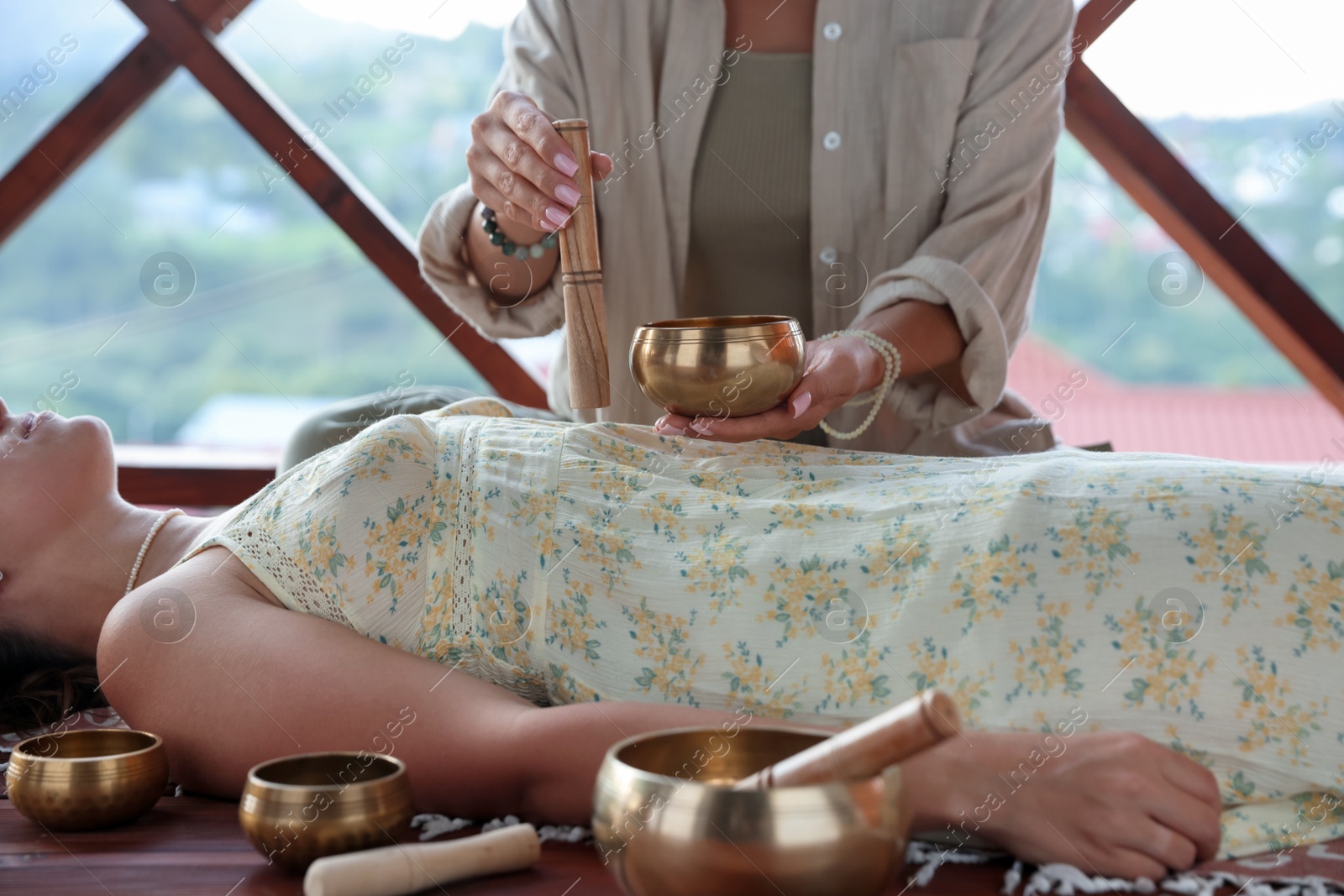 Woman undergoing singing bowl therapy lying on floor indoors, closeup Photo of Woman undergoing singing bowl therapy lying on floor indoors, closeup