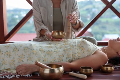 Photo of Woman undergoing singing bowl therapy lying on floor indoors, closeup