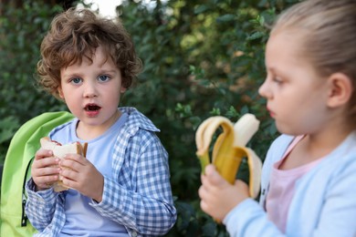 Photo of Cute kids eating food outdoors. School lunch