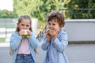 Photo of Cute kids eating food outdoors. School lunch