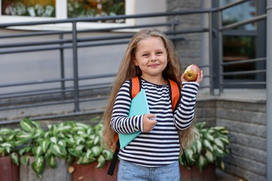 Photo of Cute little girl eating apple outdoors. School lunch