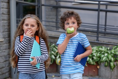 Photo of Cute little kids eating apples outdoors. School lunch