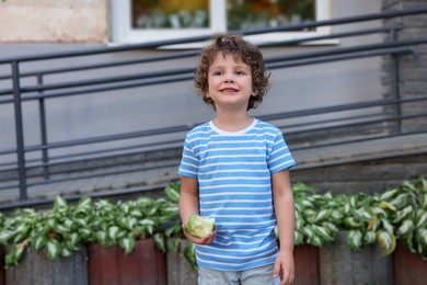 Photo of Cute little boy eating apple outdoors. School lunch