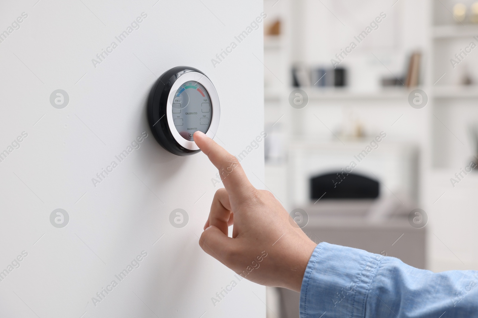 Woman adjusting hygrometer on white wall indoors, closeup. Smart home system Photo of Woman adjusting hygrometer on white wall indoors, closeup. Smart home system