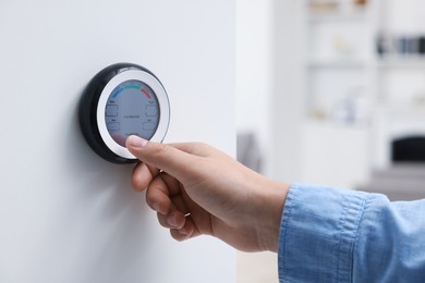 Photo of Woman adjusting hygrometer on white wall indoors, closeup. Smart home system