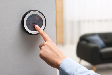 Photo of Woman adjusting hygrometer on white wall indoors, closeup. Smart home system