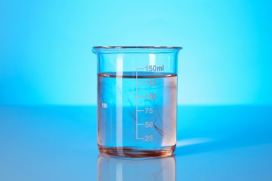 Photo of Glass beaker with dirty water on light blue background