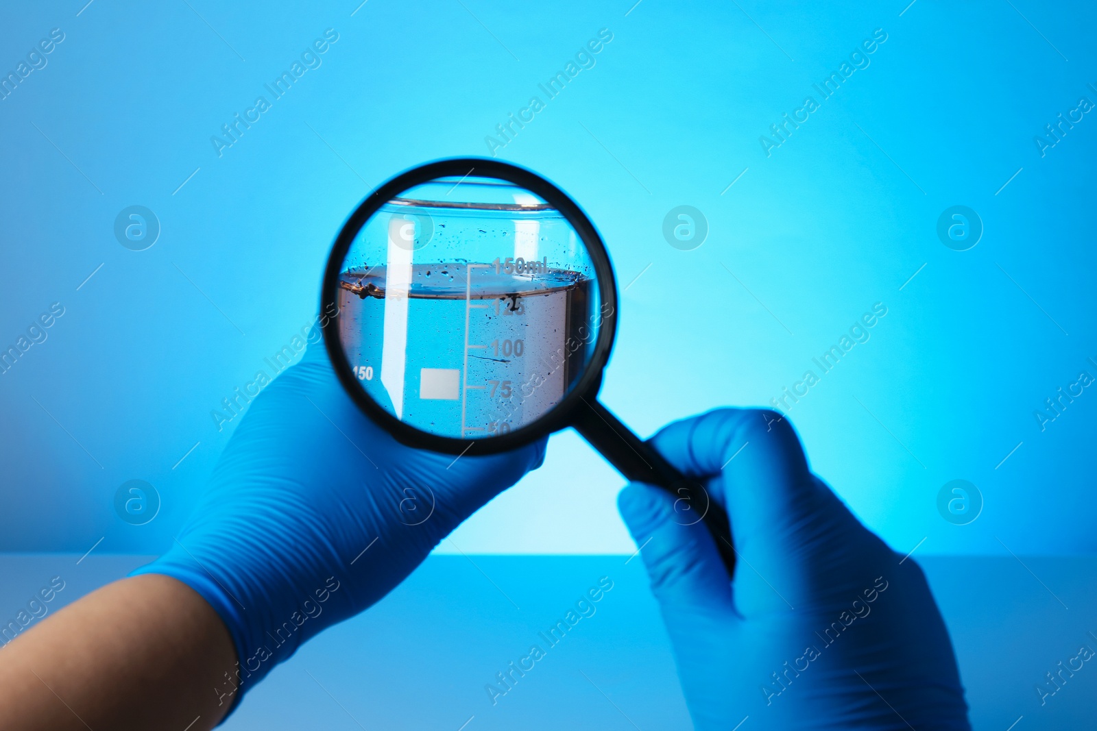 Photo of Scientist with magnifying glass and sample of water on light blue background, closeup