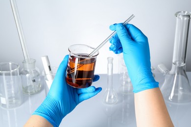 Photo of Scientist testing dirty water at white table, closeup