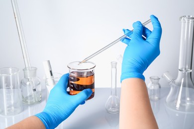 Photo of Scientist testing dirty water at white table, closeup