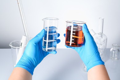 Photo of Scientist with clean and dirty water at white table, closeup