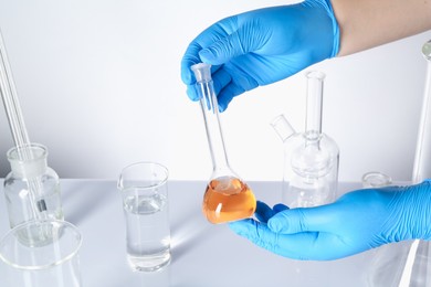 Photo of Scientist testing dirty water at white table, closeup