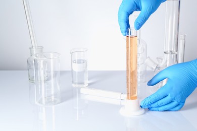 Photo of Scientist testing dirty water at white table, closeup