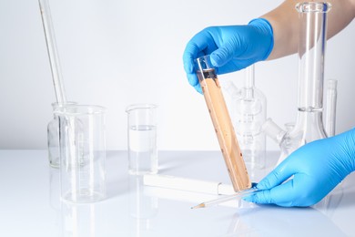 Photo of Scientist testing dirty water at white table, closeup