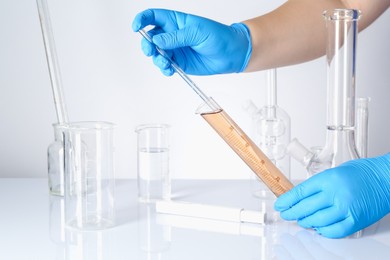 Photo of Scientist testing dirty water at white table, closeup