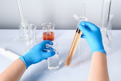 Photo of Scientist with clean and dirty water at white table, closeup