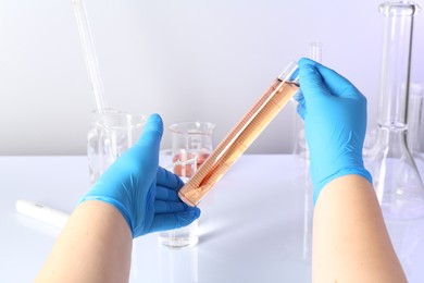 Photo of Scientist testing dirty water at white table, closeup