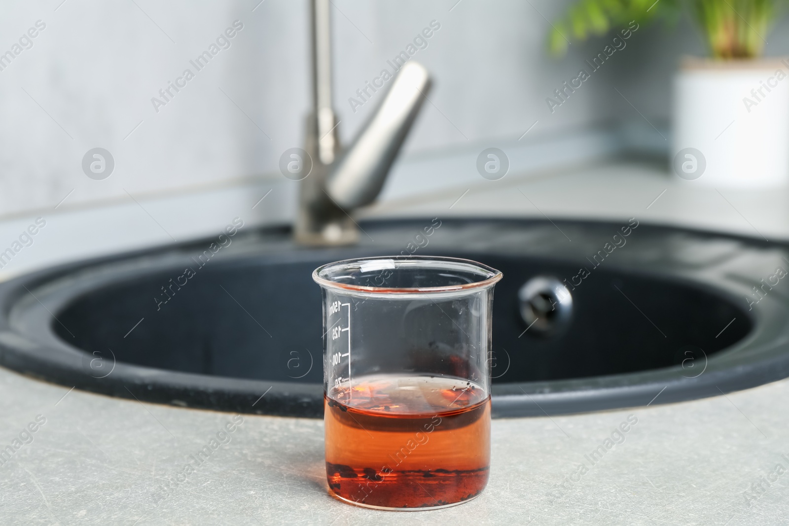 Sample of dirty water in beaker near sink indoors Photo of Sample of dirty water in beaker near sink indoors