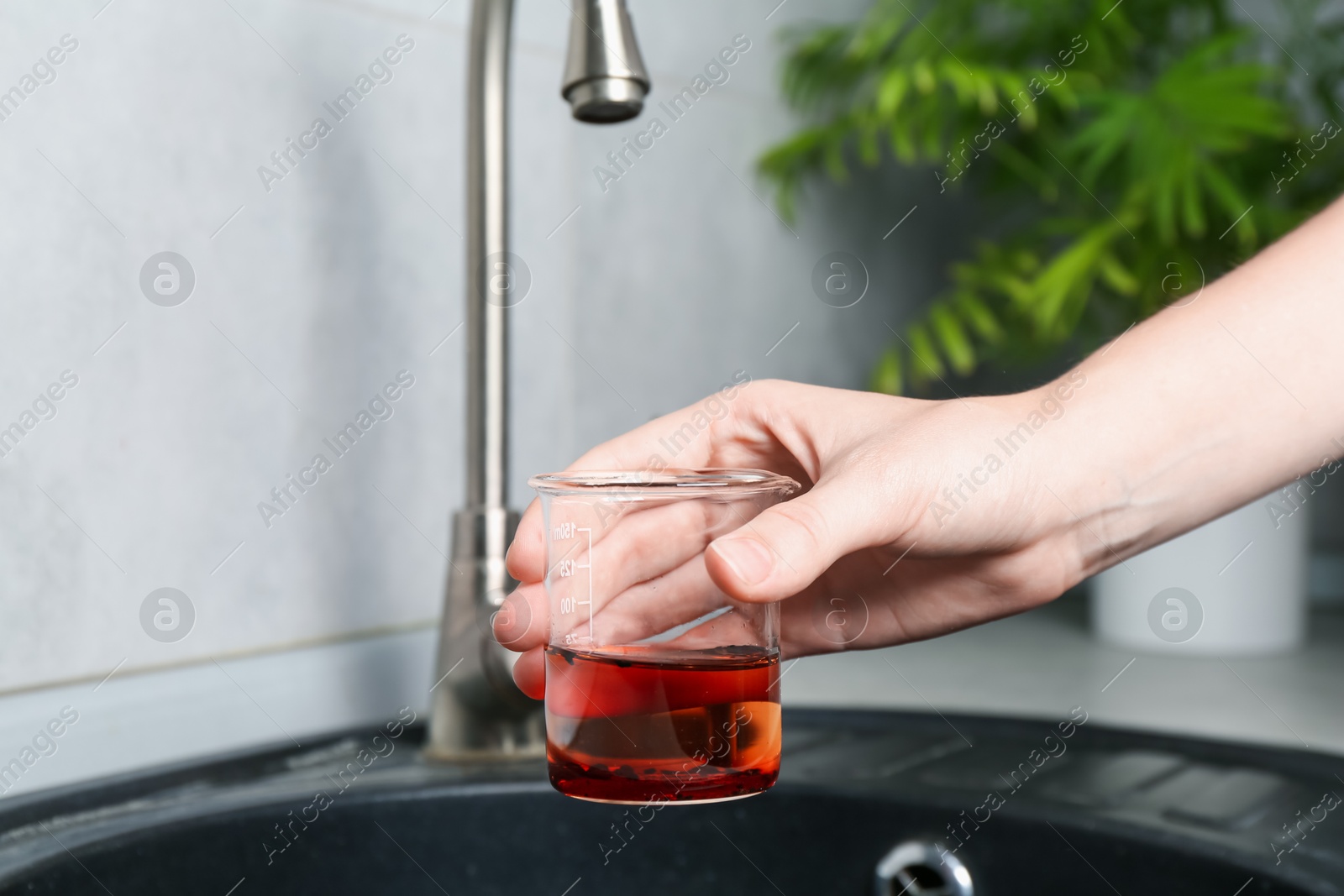 Woman taking sample of water from faucet indoors, closeup. Quality testing Photo of Woman taking sample of water from faucet indoors, closeup. Quality testing