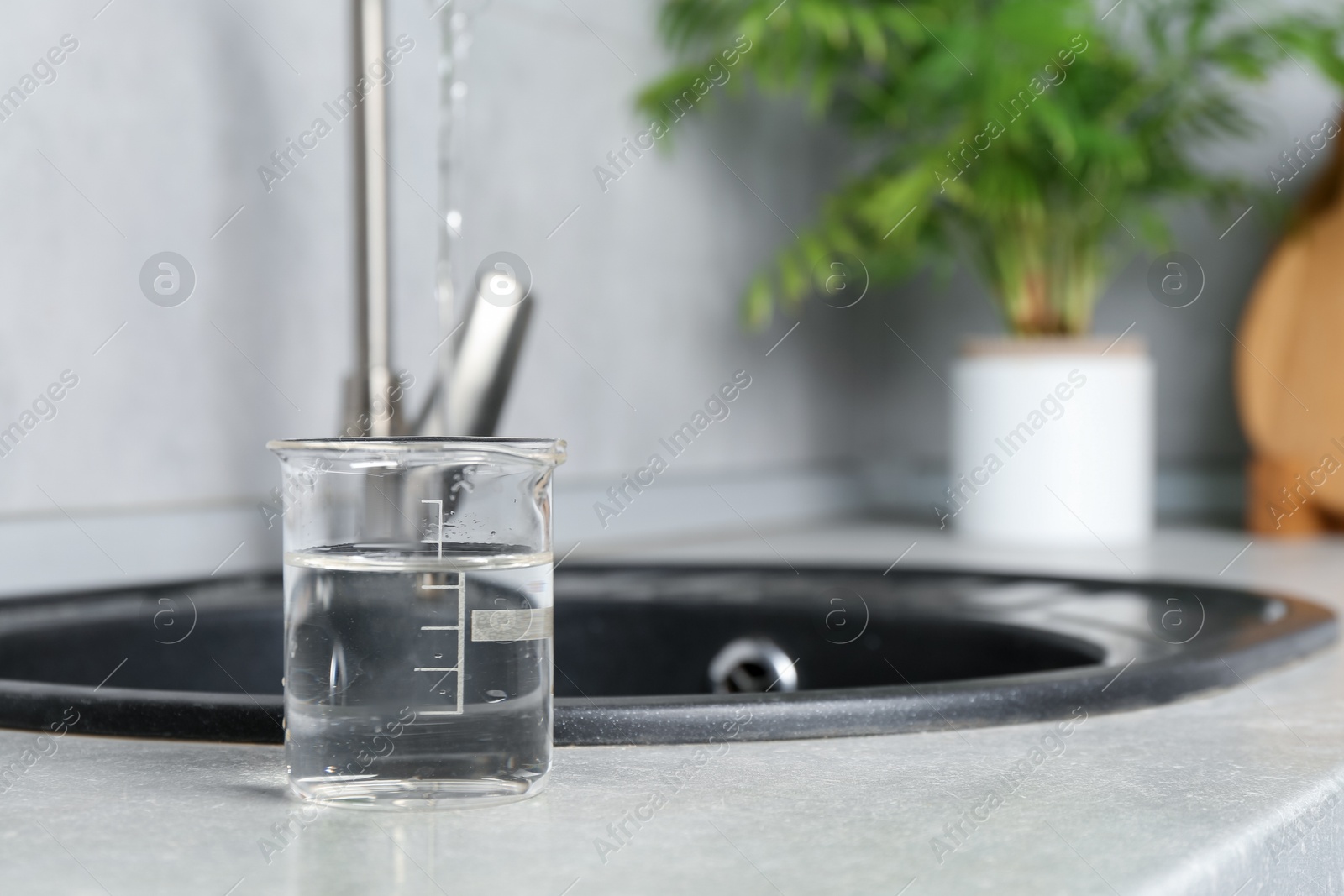Sample of water in beaker near sink indoors. Space for text Photo of Sample of water in beaker near sink indoors. Space for text