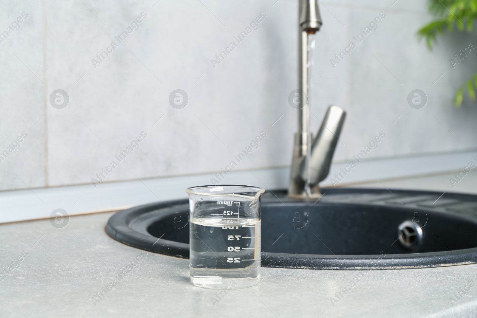 Sample of water in beaker near sink indoors. Space for text Photo of Sample of water in beaker near sink indoors. Space for text
