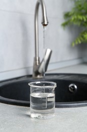 Photo of Sample of water in beaker near sink indoors