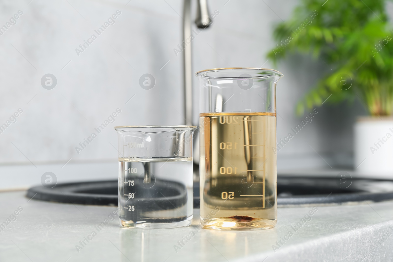 Photo of Samples of clean and dirty water near sink indoors