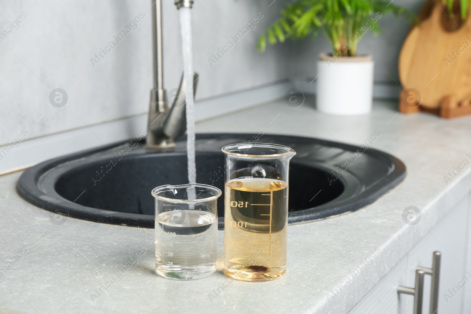 Photo of Samples of clean and dirty water near sink indoors