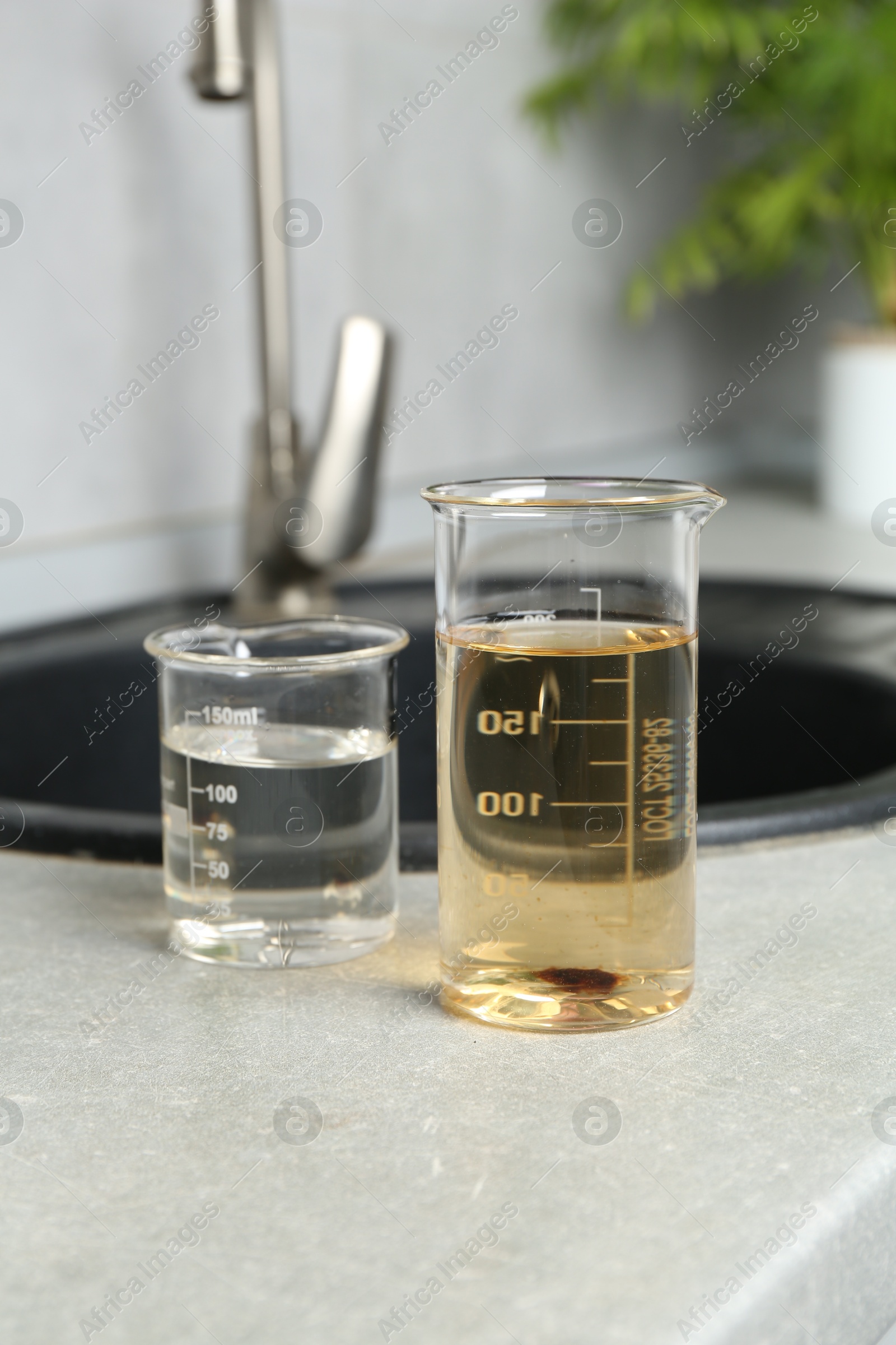 Photo of Samples of clean and dirty water near sink indoors