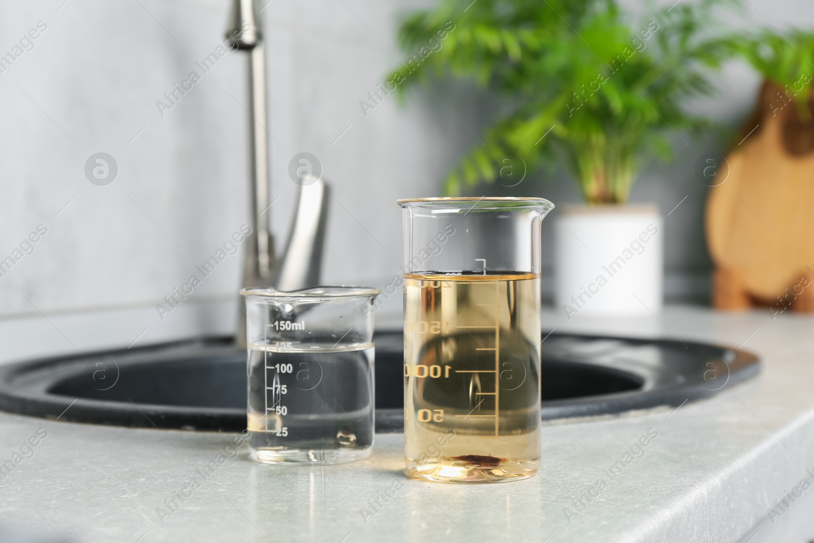 Photo of Samples of clean and dirty water near sink indoors