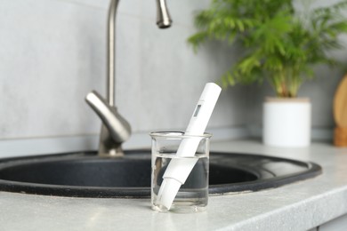 Photo of Sample of water and quality meter near sink indoors