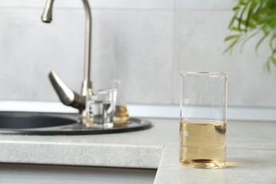 Photo of Sample of dirty water in beaker near sink indoors
