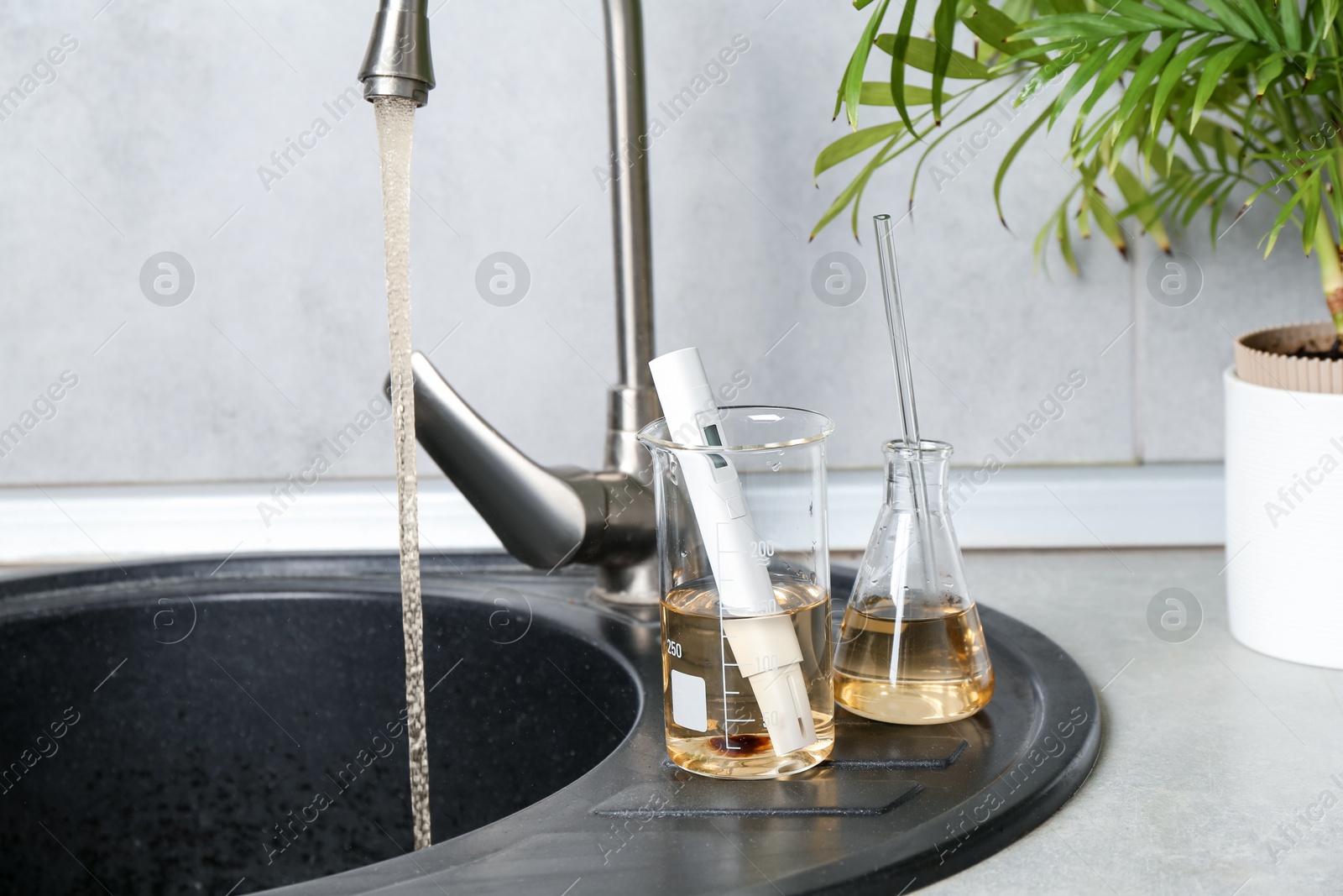Photo of Samples of dirty water and quality meter near sink indoors