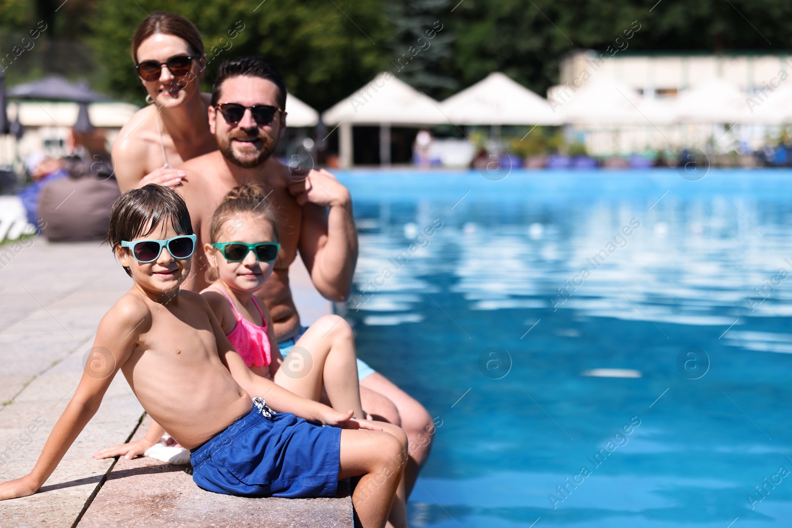 Happy family at poolside outdoors on sunny day, space for text Photo of Happy family at poolside outdoors on sunny day, space for text