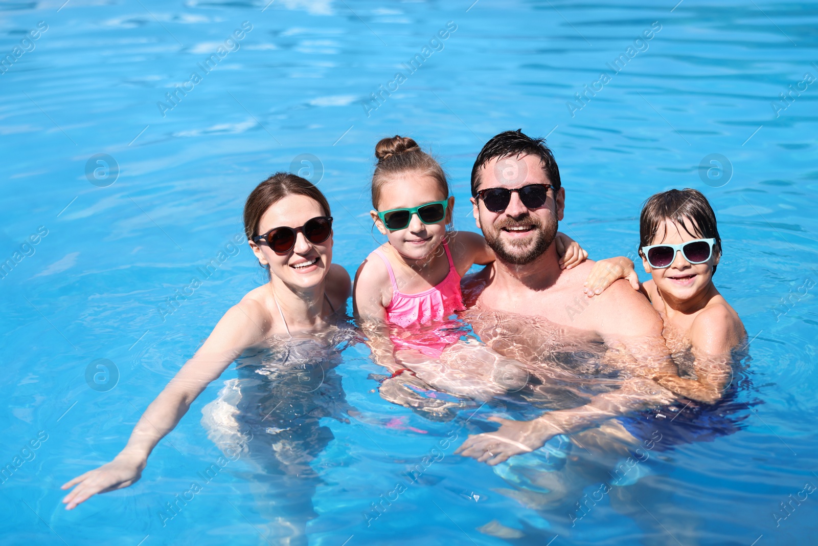 Happy family resting in swimming pool outdoors Photo of Happy family resting in swimming pool outdoors