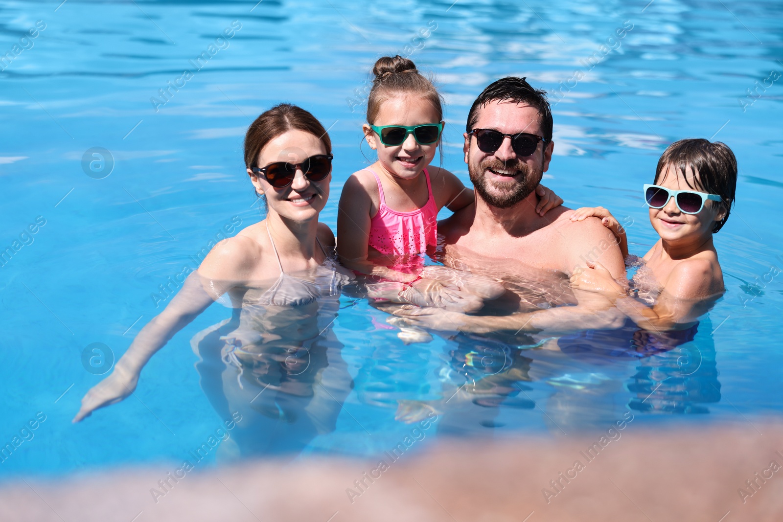 Happy family resting in swimming pool outdoors Photo of Happy family resting in swimming pool outdoors
