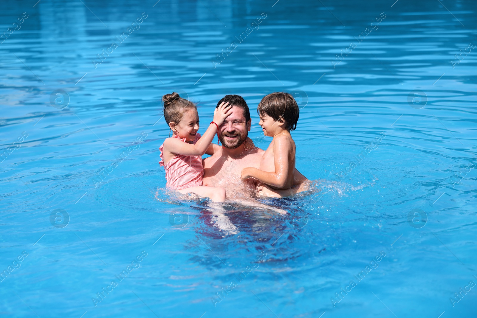 Father and his kids having fun in swimming pool outdoors. Family vacation Photo of Father and his kids having fun in swimming pool outdoors. Family vacation