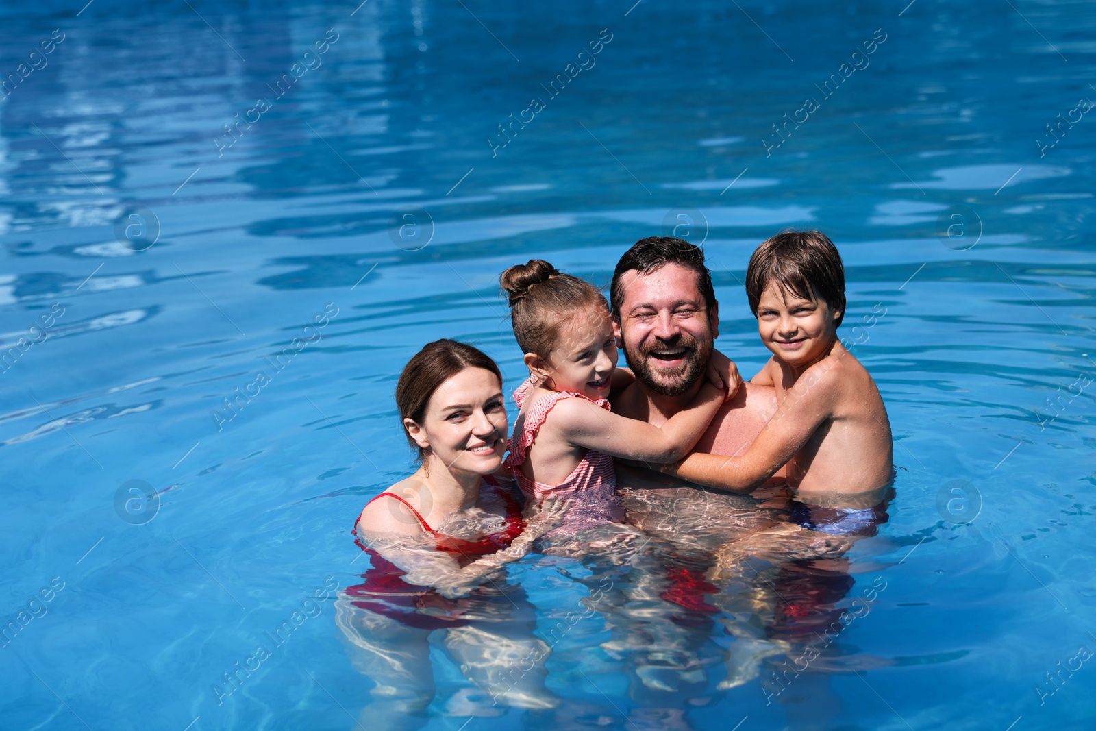 Happy family resting in swimming pool outdoors Photo of Happy family resting in swimming pool outdoors